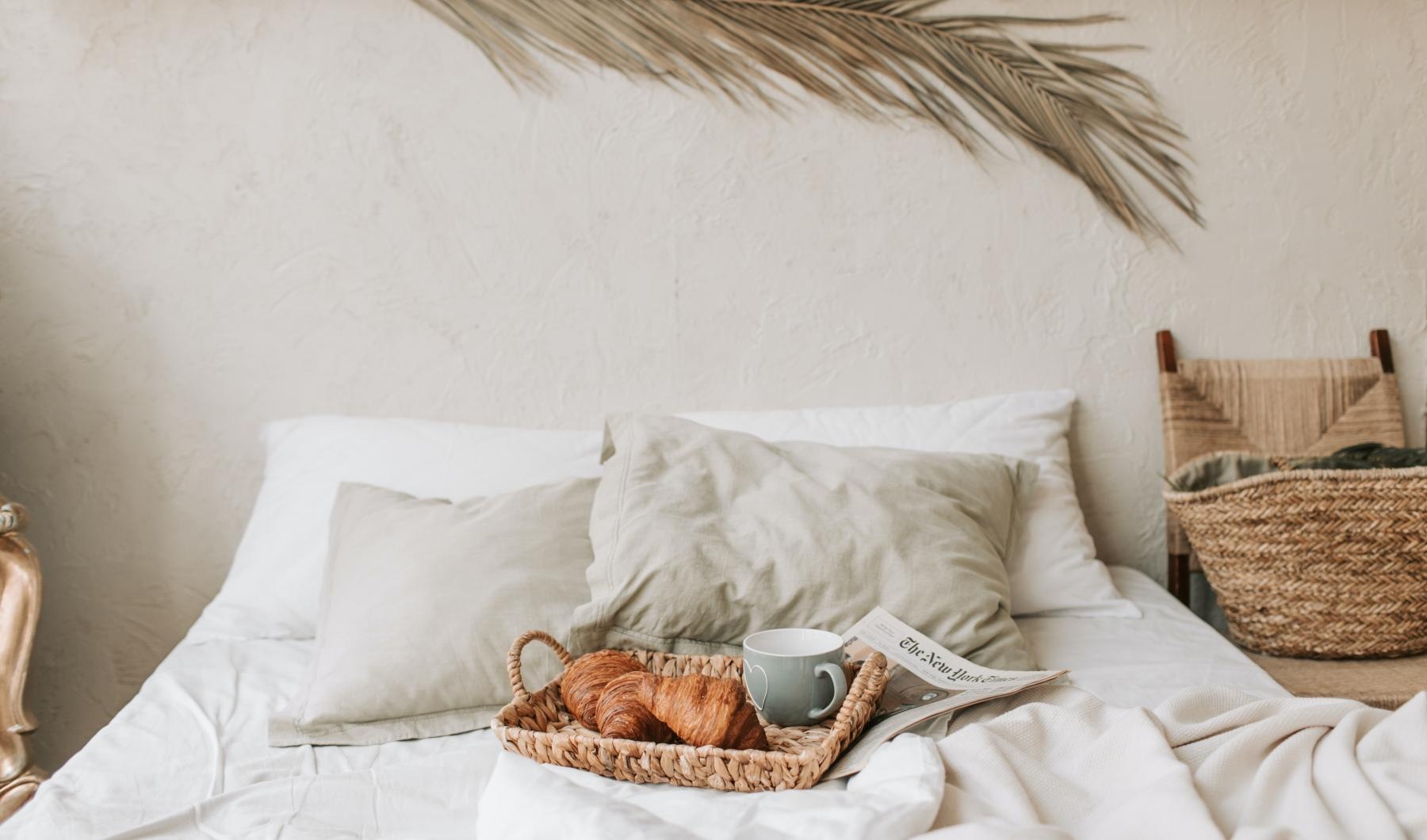 a bed with a cup of coffee and a newspaper on it